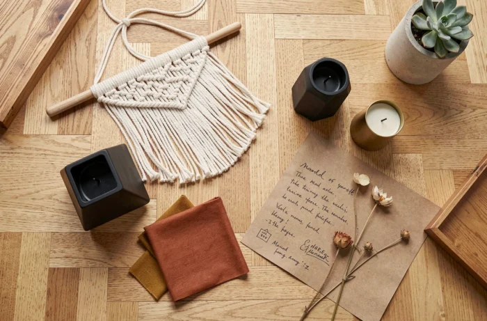 Flat lay créatif d'objets décoratifs tendance à petit prix sur parquet en chêne, incluant macramé, bougeoirs géométriques et moodboard kraft